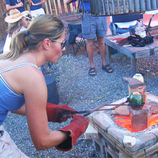 woman holding tongs firing open kiln uvapapa Villa Grove San Luis Valley colorado pottery fireweed studio jenn weede